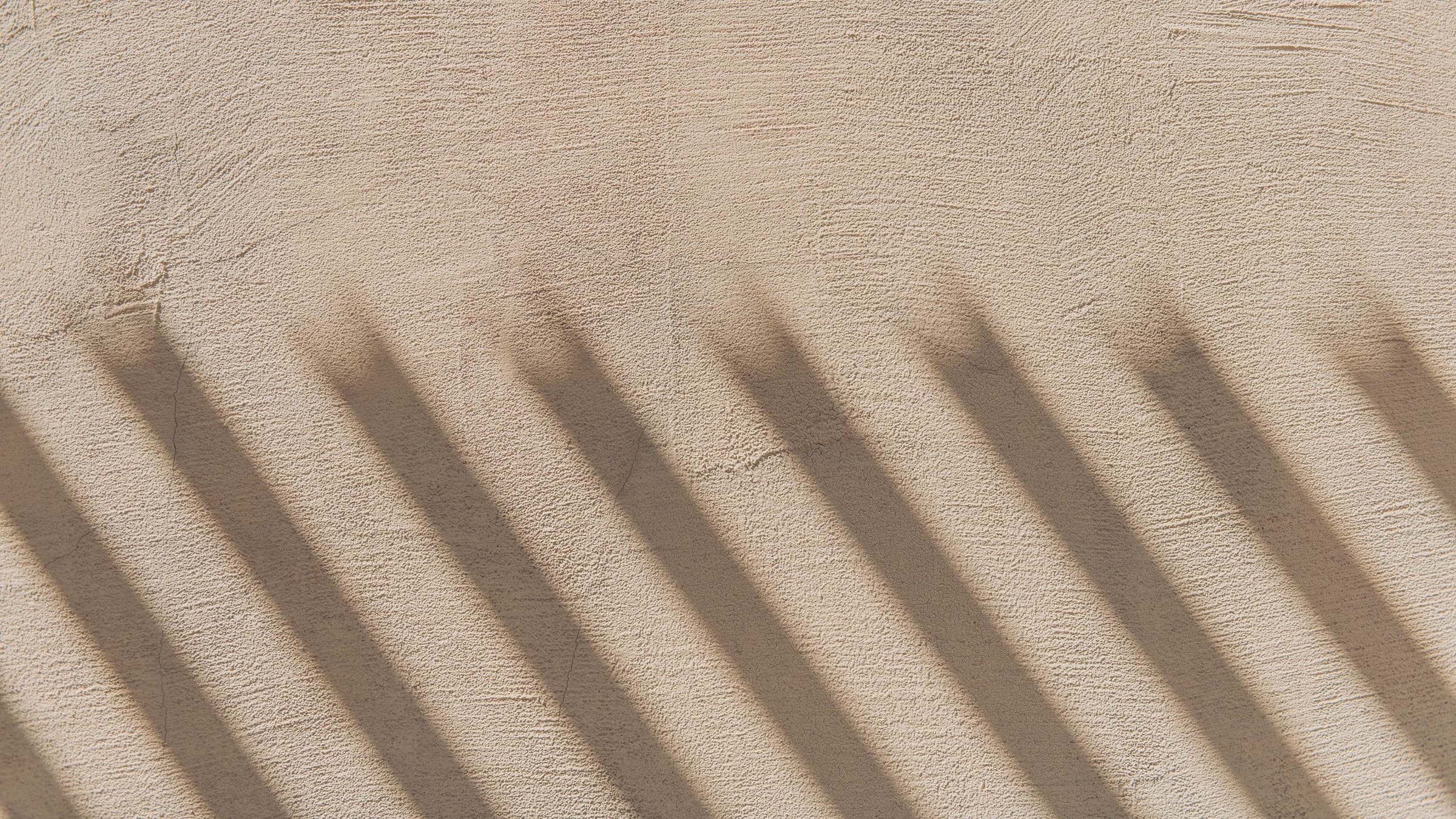 Daylight from a window across a plaster wall